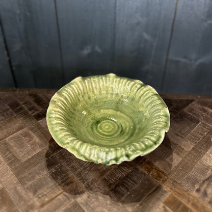 Green ceramic bowl on a textured surface with a dark wooden background