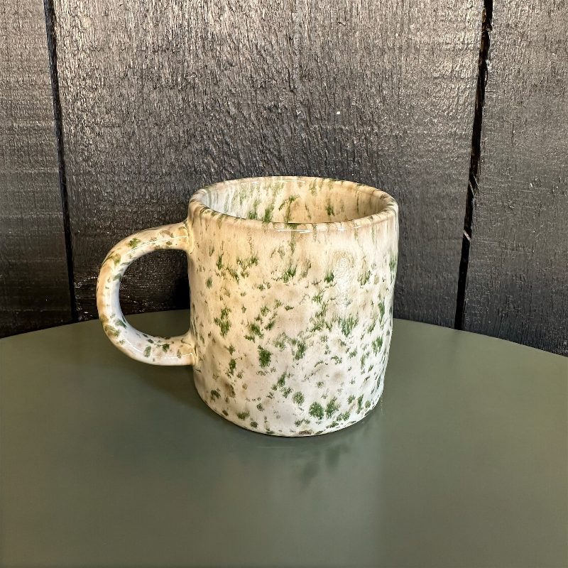 Speckled ceramic mug on a dark surface with a textured black background