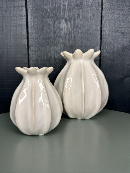 Two white ceramic vases on a gray surface with a dark wooden background