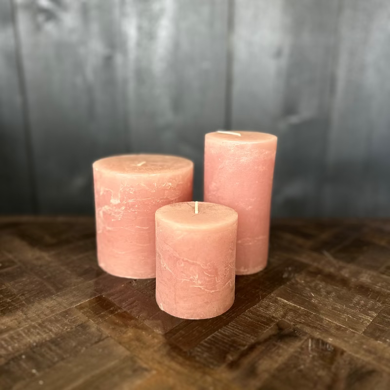Three pink candles on a wooden surface with a dark background