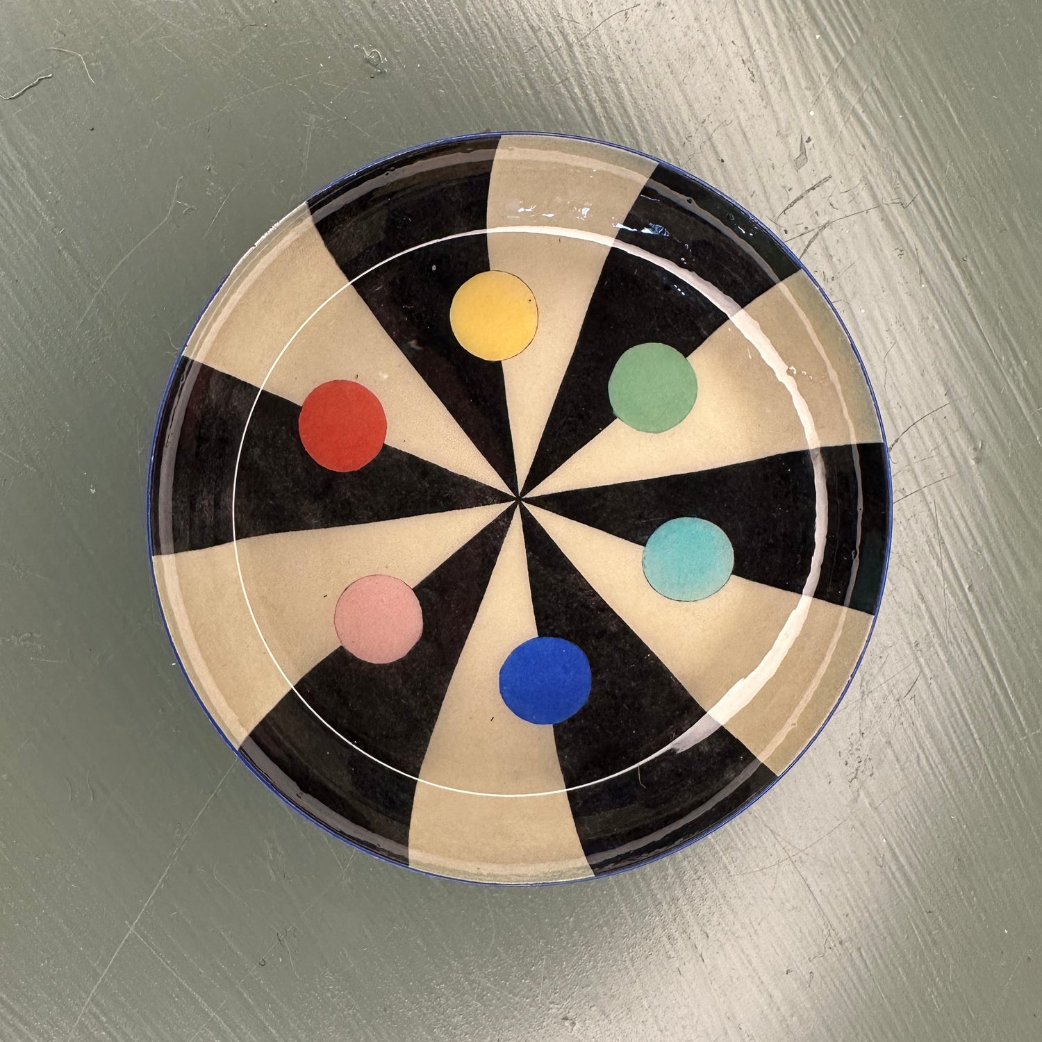 Decorative plate with colourful dots on a green surface