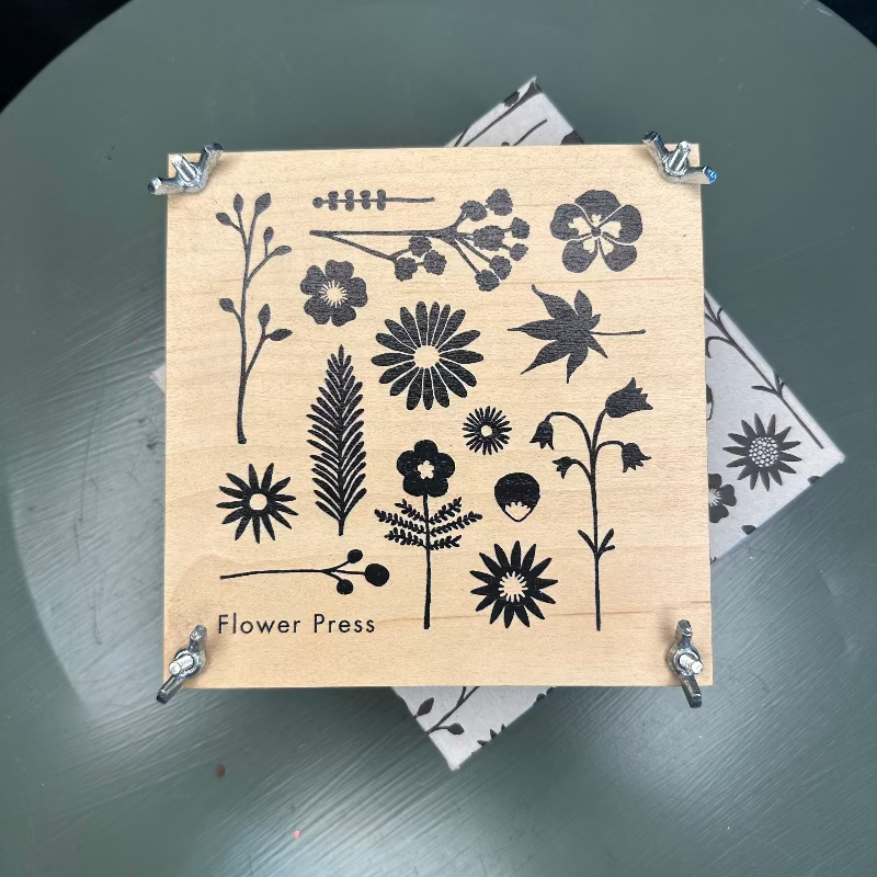 Wooden flower press with floral designs on a dark surface