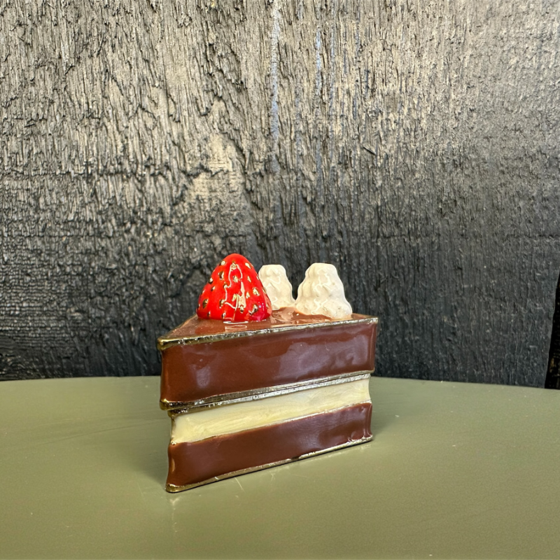 Miniature layered cake with red and white decorations on a green surface with a dark textured background
