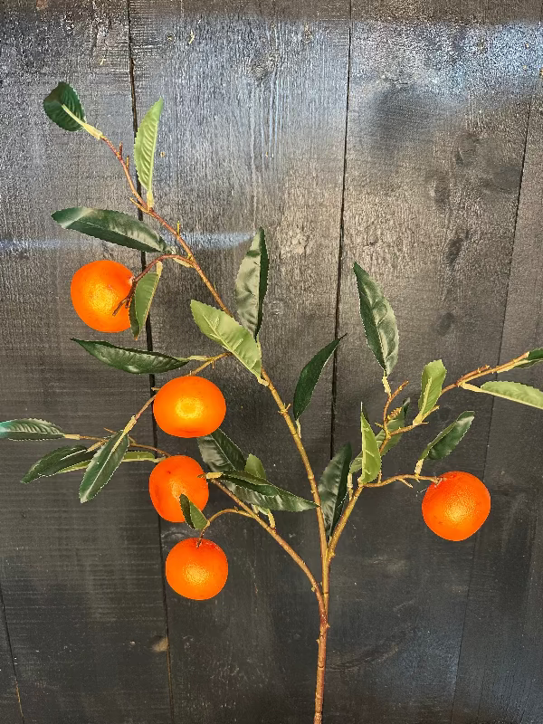 Artificial orange tree branch with oranges against a wooden background