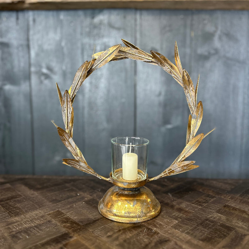 Decorative candle holder with leaf design on a wooden surface and gray wall background