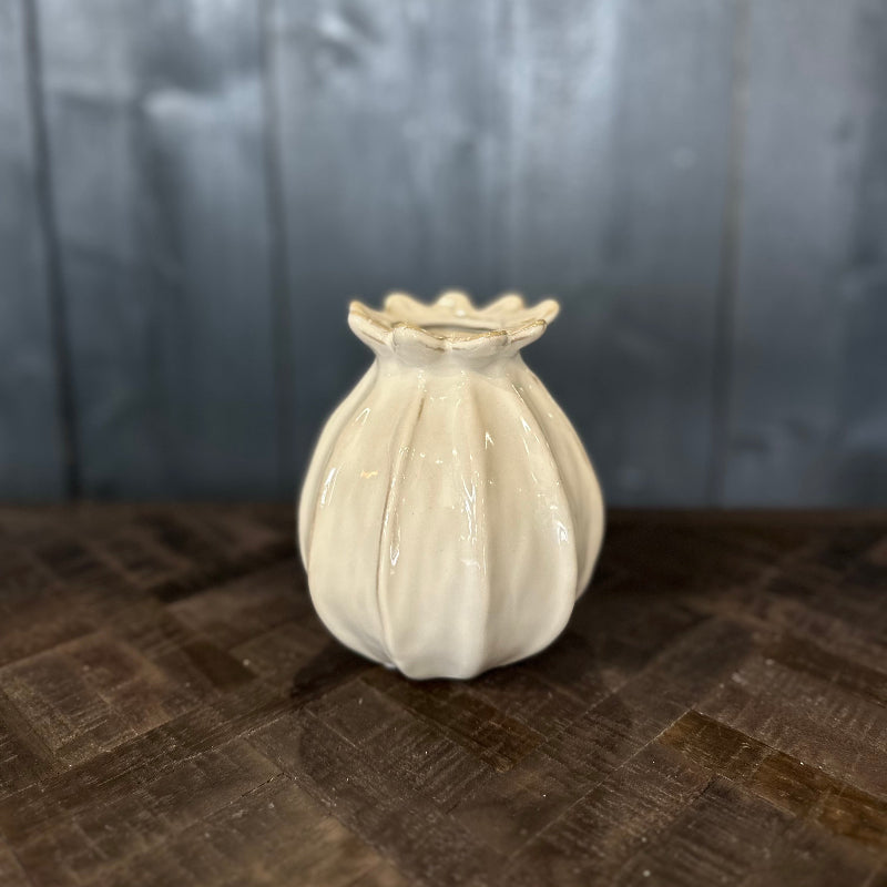 Small white ceramic vase on a textured surface with a neutral background