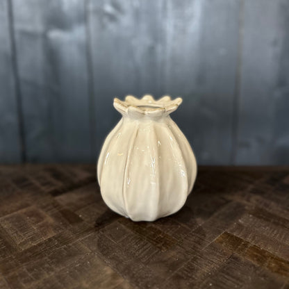 Small white ceramic vase on a textured surface with a neutral background