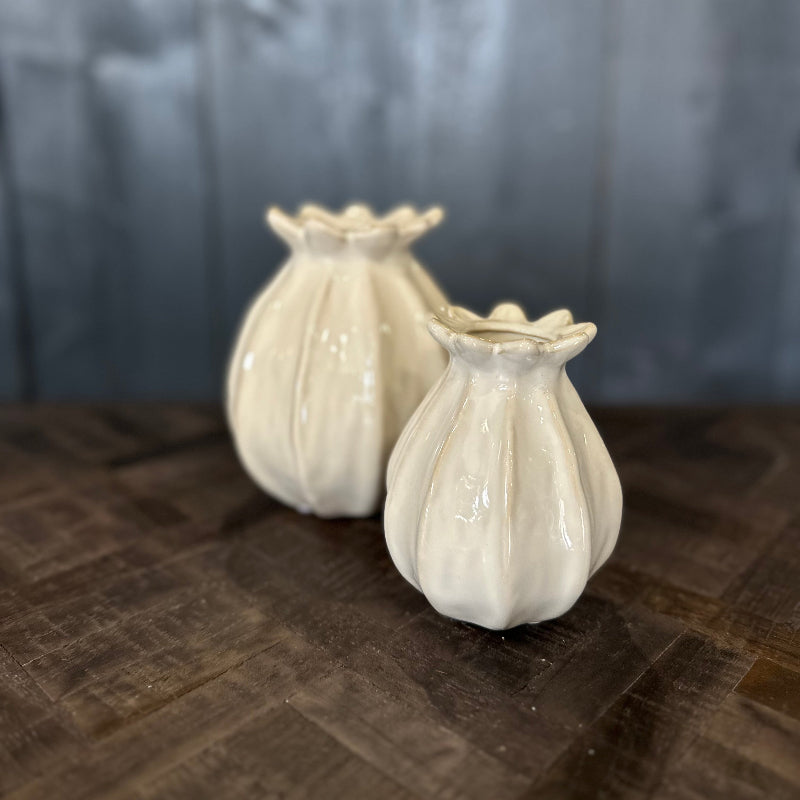 Two white ceramic vases on a wooden surface with a gray background