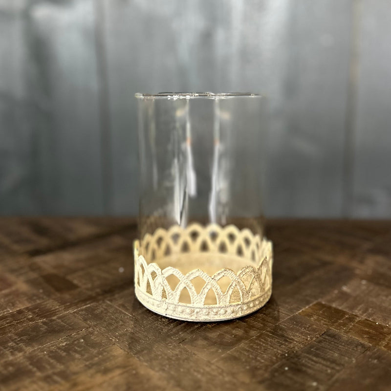 Clear glass candle holder with decorative lace-like base on a wooden surface