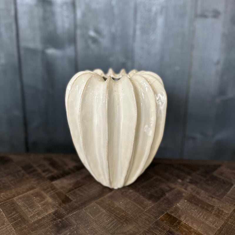White textured vase on a wooden surface with a dark wooden panel background