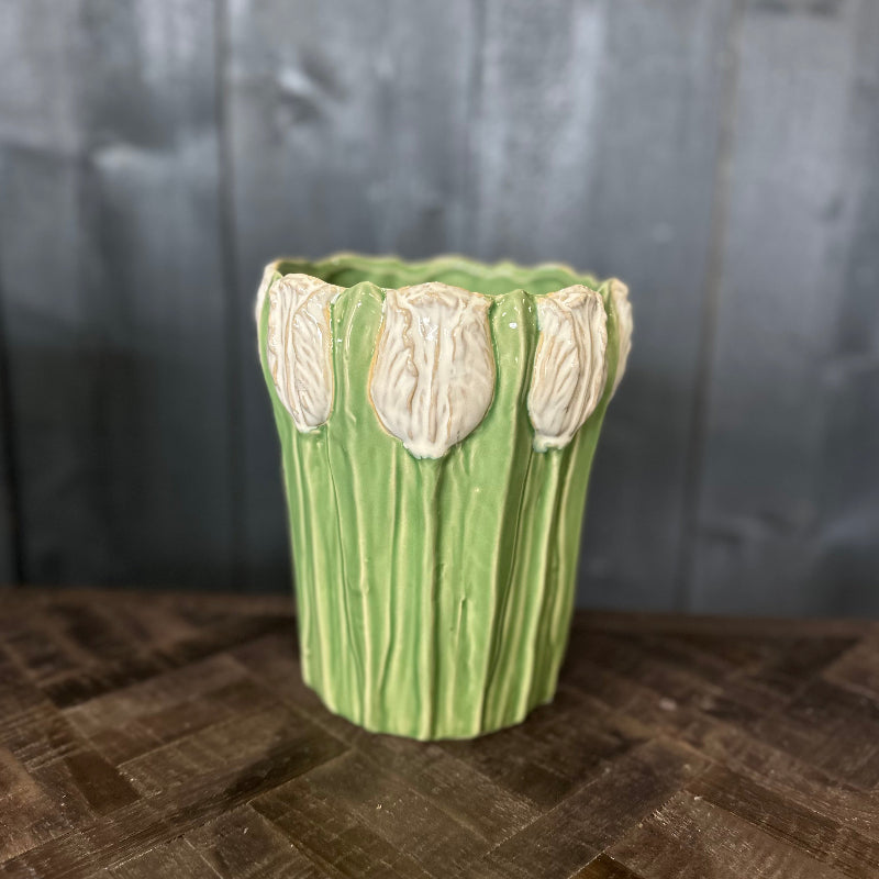 Green ceramic vase with floral designs on a wooden surface