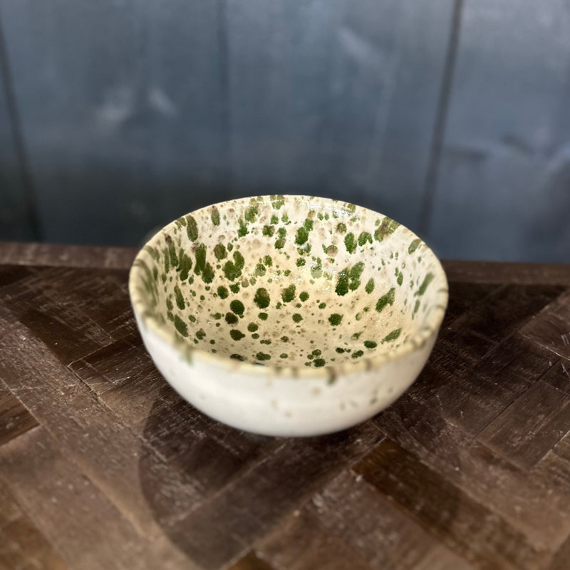 Speckled ceramic bowl on a textured surface with a dark background