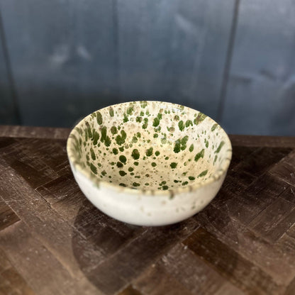 Speckled ceramic bowl on a textured surface with a dark background