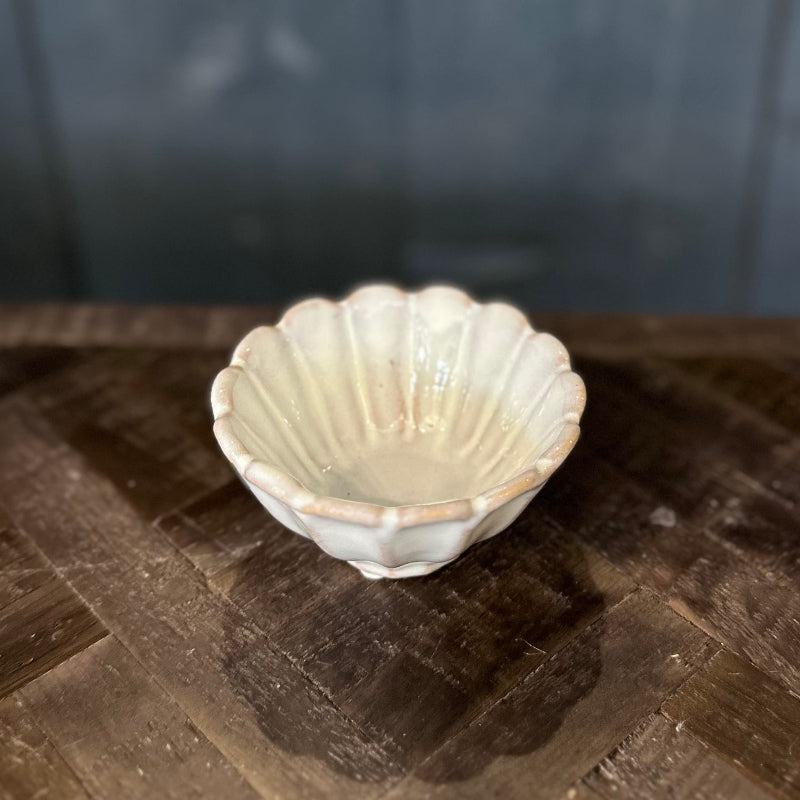 Shell-shaped ceramic bowl on a wooden surface with a dark background