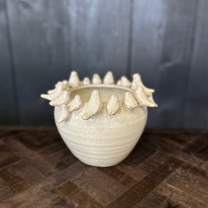 White ceramic vase with bird-like decorations on a dark wooden surface