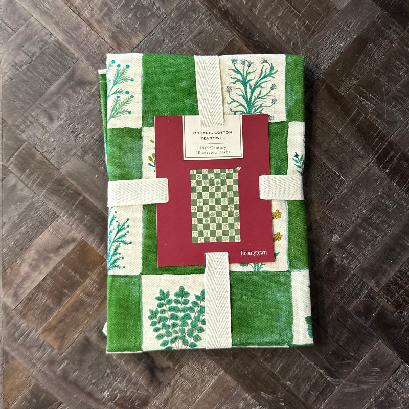 Set of green and white patterned tea towels with a red box on a wooden surface