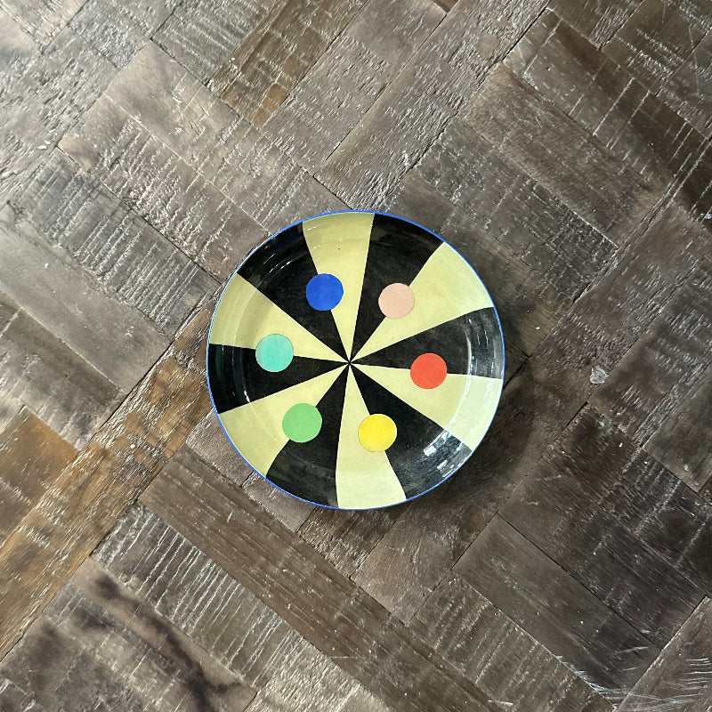 Round plate with colorful dots on a wooden surface
