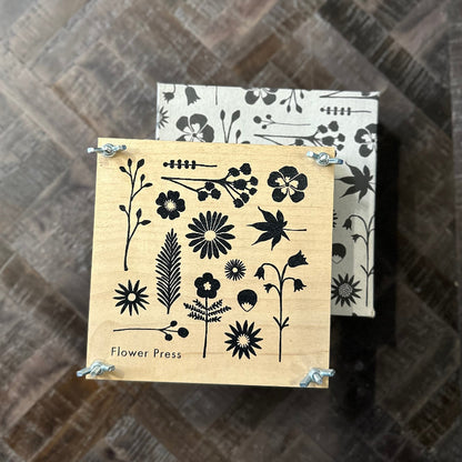 Wooden flower press with black floral designs on a wooden surface