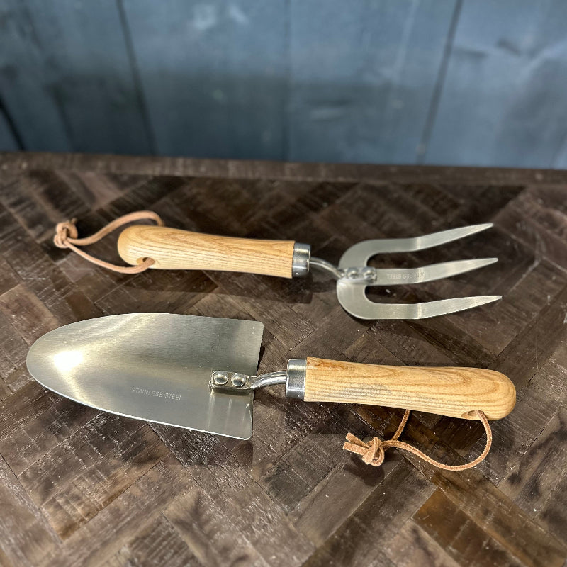 Two gardening tools with wooden handles on a textured surface