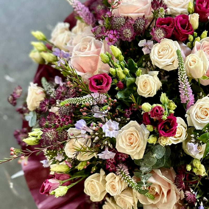Bouquet of flowers with a mix of pink, white, and purple roses on a gray background
