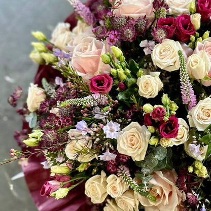 Bouquet of flowers with a mix of pink, white, and purple roses on a gray background