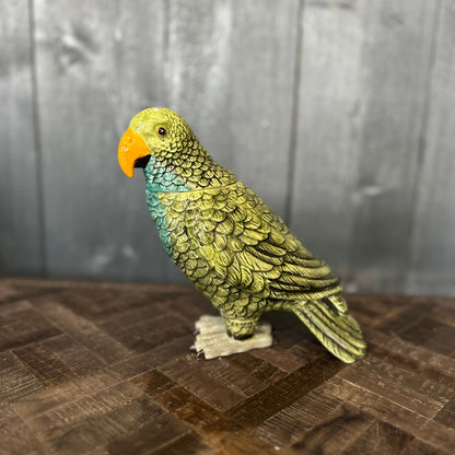 Green parrot figurine on a wooden surface with a gray background