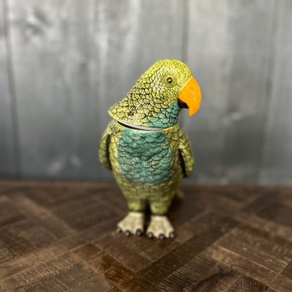 Green parrot-shaped teapot on a wooden surface with a gray background
