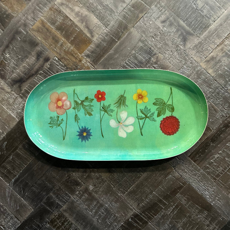 Green tray with floral designs on a wooden surface