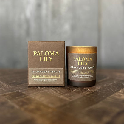Paloma Lily candle and packaging on a wooden surface with a blurred background