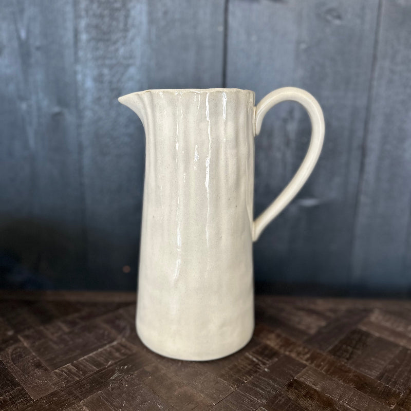 White ceramic pitcher on a wooden surface with a dark background