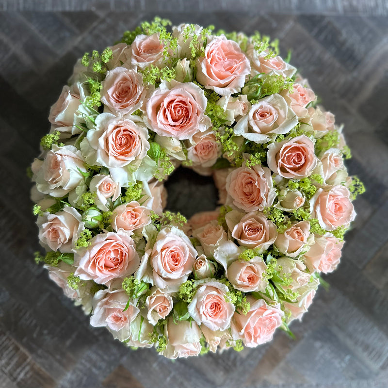 Floral wreath with pink and white roses on a textured surface