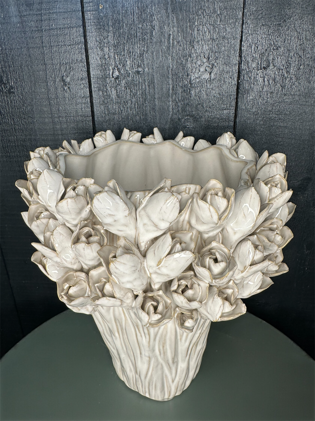 Decorative ceramic vase with floral design against a dark wooden panel background