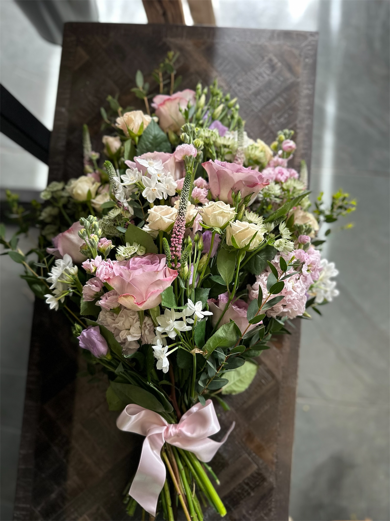 Bouquet of flowers with a pink ribbon on a wooden stand.